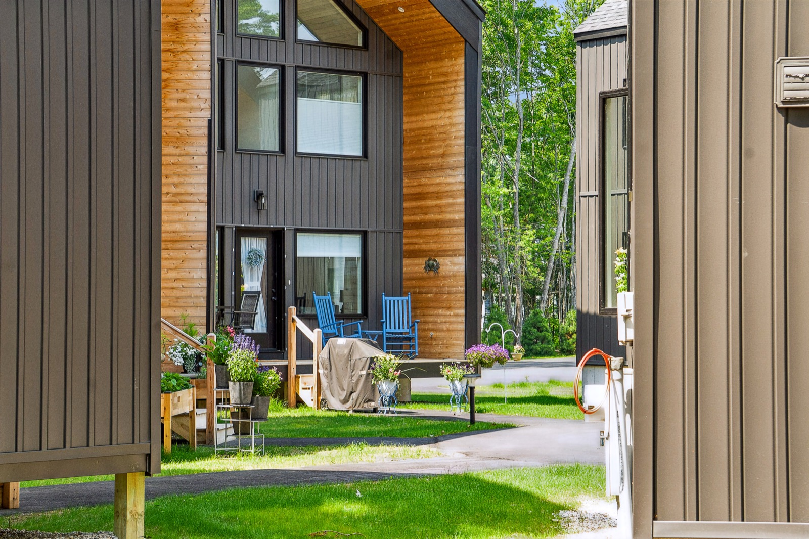 A Wilbur's Woods home with a covered front deck, blue chairs and planters