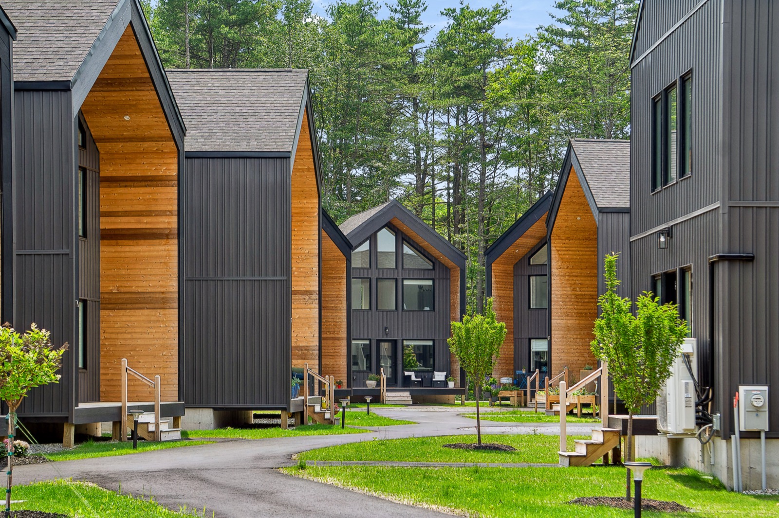 Dark-sided homes with cedar accents along a curving street at Wilbur's Woods, Brunswick, Maine
